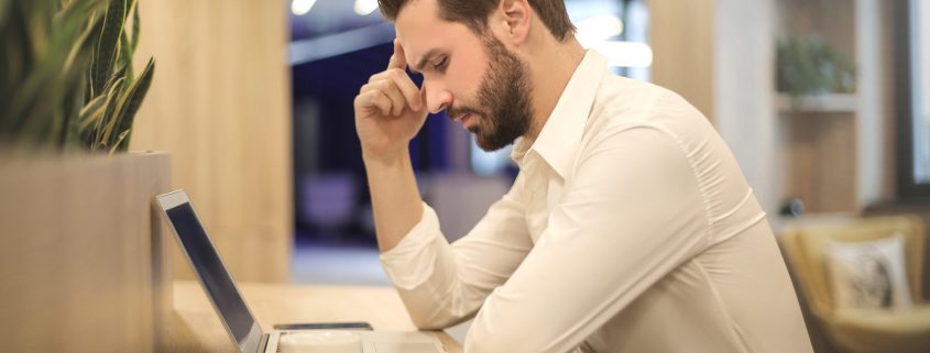 Man looking at a laptop and thinking about back office services